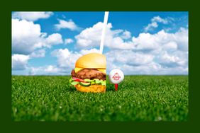 Photo illustration of an Arby's hamburger and golf ball in grass with cloudy sky.