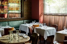 Tables set in restaurant with wine glasses and cutlery.