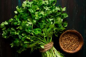 A bunch of fresh Cilantro and a small bowl of coriander seeds.