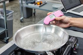 Hand measuring the temperature of the All-Clad 10-Inch D3 Stainless 3-Ply Bonded Cookware 