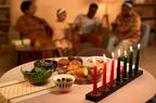 Colorful burning candles and tasty dishes on table in living room of family celebrating Kwanzaa