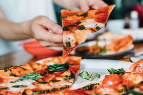 Hand grabbing a slice of pizza