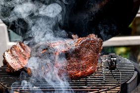 Meat being smoked in a grill.