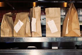 Food in take out bags with receipts, sitting on restaurant shelf.