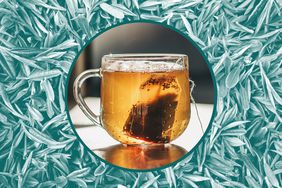 A tea cup and bag over a background of tea leaves. 