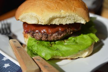 A hamburger on a plate with a knife and fork. 